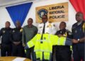 Senator Momo Cyrus presents a customized reflective rain jacket to Inspector General Gregory Coleman and Liberia National Police officers at LNP headquarters in Monrovia.