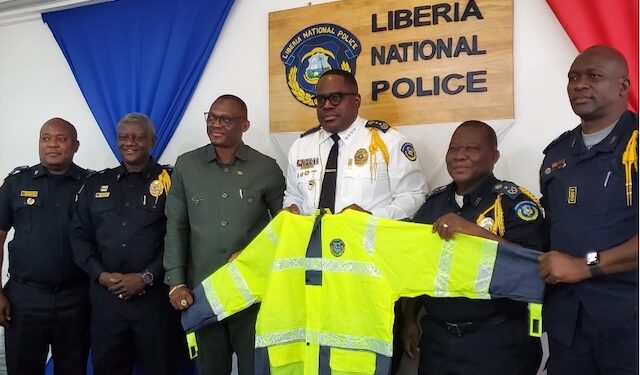 Senator Momo Cyrus presents a customized reflective rain jacket to Inspector General Gregory Coleman and Liberia National Police officers at LNP headquarters in Monrovia.