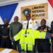 Senator Momo Cyrus presents a customized reflective rain jacket to Inspector General Gregory Coleman and Liberia National Police officers at LNP headquarters in Monrovia.