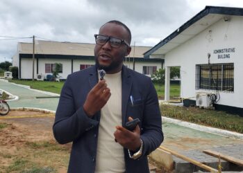 Dr. Isaac P. Podah, President of Lofa County University, speaks on campus during a transformation update, with administrative buildings in the background.