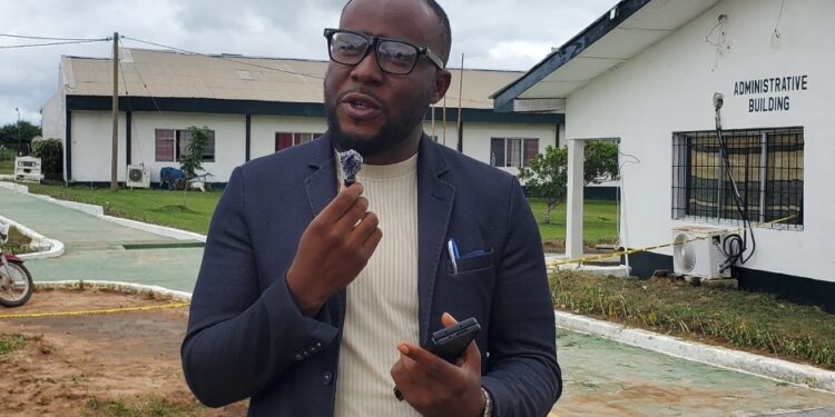 Dr. Isaac P. Podah, President of Lofa County University, speaks on campus during a transformation update, with administrative buildings in the background.