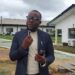 Dr. Isaac P. Podah, President of Lofa County University, speaks on campus during a transformation update, with administrative buildings in the background.