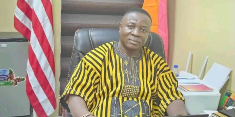 Rep. Prince Koinah seated at his office desk, wearing traditional Liberian attire, amid growing backlash from Kpaai Town residents over stalled campaign projects and poor road conditions.