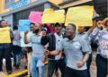 Citizens protest in front of the Ministry of Transport in Monrovia, holding placards demanding faster passport processing and license issuance.