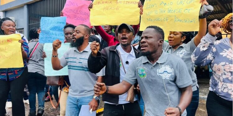 Citizens protest in front of the Ministry of Transport in Monrovia, holding placards demanding faster passport processing and license issuance.