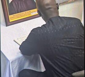 Former Liberian President George Weah signs the Book of Condolence in Abuja for late Nigerian President Muhammadu Buhari, whose framed portrait is displayed beside him, during a solemn tribute honoring Buhari’s legacy as a regional pillar of stability