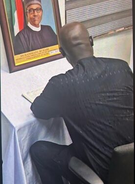 Former Liberian President George Weah signs the Book of Condolence in Abuja for late Nigerian President Muhammadu Buhari, whose framed portrait is displayed beside him, during a solemn tribute honoring Buhari’s legacy as a regional pillar of stability