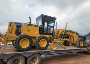Caterpillar motor grader loaded on trailer for transport to road construction site in Liberia