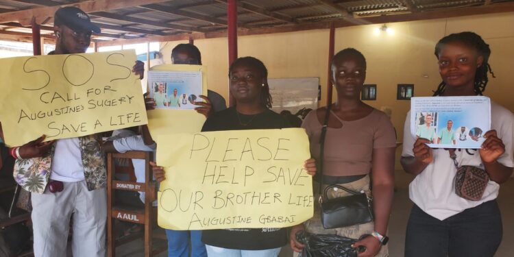 University of Liberia students hold placards appealing for help to fund heart surgery for their classmate Augustine Gbabai