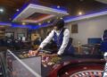 Casino dealer in uniform arranging chips on a roulette table at 50/50 Casino in Monrovia, Liberia.