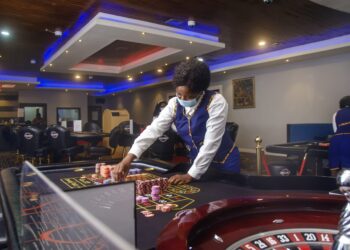Casino dealer in uniform arranging chips on a roulette table at 50/50 Casino in Monrovia, Liberia.