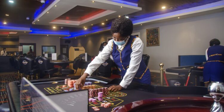Casino dealer in uniform arranging chips on a roulette table at 50/50 Casino in Monrovia, Liberia.