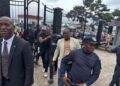 Fobay Emery Johnson, alleged Ecobank robbery suspect, escorted by police officers outside the Monrovia City Court gate after being charged with armed robbery and attempted murder.