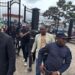 Fobay Emery Johnson, alleged Ecobank robbery suspect, escorted by police officers outside the Monrovia City Court gate after being charged with armed robbery and attempted murder.