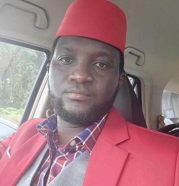 Former Liberian footballer Emmanuel Wennah in a red suit and cap, preparing to launch the Play With Purpose sports reform initiative