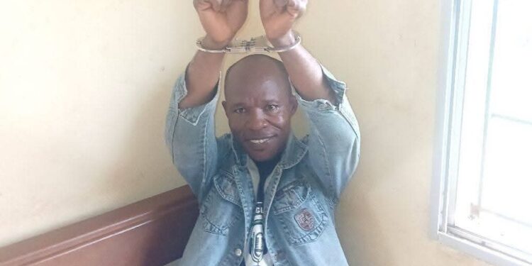 Liberian journalist Eric Opa Doue in handcuffs raising his hands, following a second attempted arrest in River Cess County