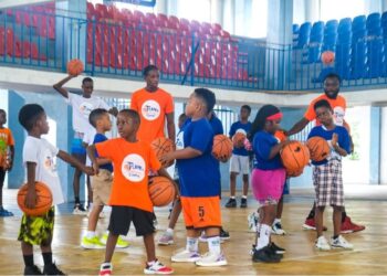 Young participants at Flames Basketball youth camp in Monrovia practicing dribbling drills on the court with coaches