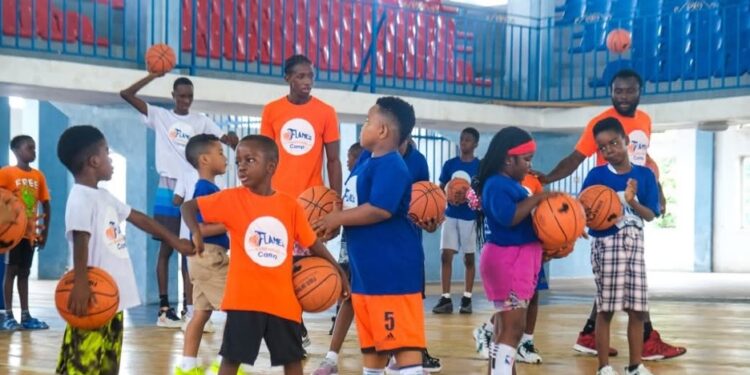 Young participants at Flames Basketball youth camp in Monrovia practicing dribbling drills on the court with coaches
