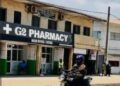 G-2 Pharmacy storefront in Monrovia, Liberia, with a commercial motorcyclist passing by on the main street in front of the head office.