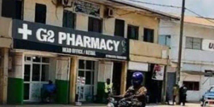 G-2 Pharmacy storefront in Monrovia, Liberia, with a commercial motorcyclist passing by on the main street in front of the head office.