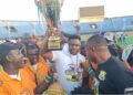 FC Fassell CEO and LFA presidential hopeful Cassell Kuoh celebrating with a trophy surrounded by supporters at a football stadium