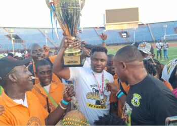 FC Fassell CEO and LFA presidential hopeful Cassell Kuoh celebrating with a trophy surrounded by supporters at a football stadium