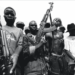 Former Liberian combatants holding assault rifles during the civil war, symbolizing the legacy of violence that transitional justice efforts aim to address.