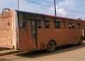 Two National Transit Authority buses in Liberia—one rusted and parked, the other surrounded by stranded commuters in Maryland County amid rising fare concerns.