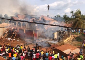 Crowds watch as smoke rises from a destroyed home and storage facility during a major fire in Pleebo City, Maryland County, Liberia