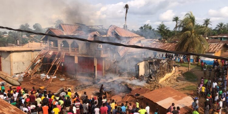 Crowds watch as smoke rises from a destroyed home and storage facility during a major fire in Pleebo City, Maryland County, Liberia