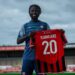 Liberian midfielder Mohammed Sangare holds his new Morecambe FC jersey after signing for the English National League side for the 2025-26 season