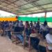 Over 100 Tubman University students seated in pavilion-turned-lecture hall as enrollment surge pushes administrators to expand learning spaces.