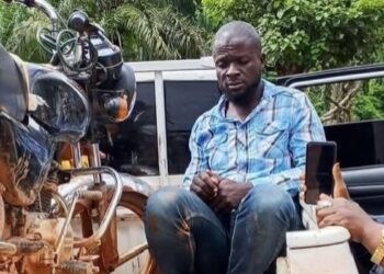 Arrested Radio BKS staff member seated near a motorcycle after being detained for allegedly carrying a locally made firearm in Nimba County on election day.