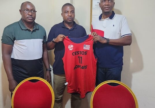 Cestos Mogars Basketball Club and Bukonjadeh Group of Companies executives hold up the team’s jersey after signing a one-year sponsorship deal in Monrovia