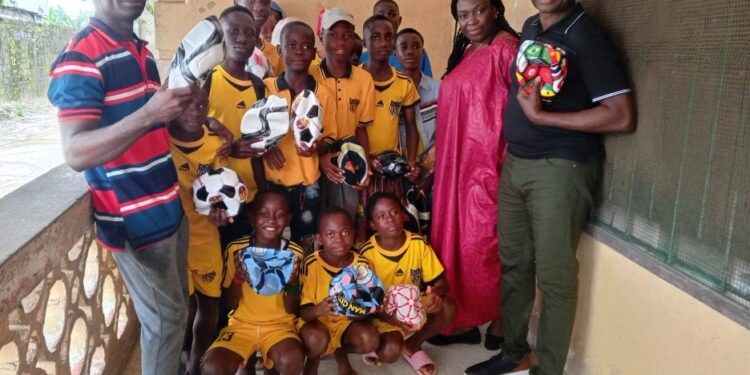 Sonia Harrison, CEO of the Fatimah Project, poses with ANSSA players after donating footballs in Monrovia.