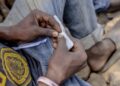 Close-up of a man’s hands rolling a drug joint, symbolizing Liberia’s growing narcotics crisis