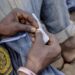 Close-up of a man’s hands rolling a drug joint, symbolizing Liberia’s growing narcotics crisis