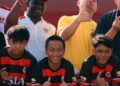 Liberian football coach Albert Kamara sits beside academy staff and regional sports officials during a youth football development session in Brunei.