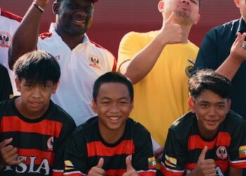 Liberian football coach Albert Kamara sits beside academy staff and regional sports officials during a youth football development session in Brunei.