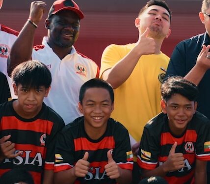 Liberian football coach Albert Kamara sits beside academy staff and regional sports officials during a youth football development session in Brunei.