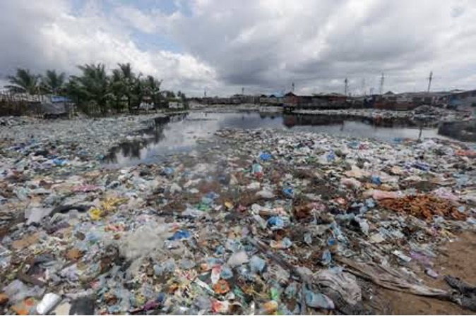 Plastic waste and pollution cover a beach shoreline in Liberia, symbolizing environmental degradation.