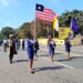 Ladies of Marshall members in ceremonial uniforms marching with the Liberian flag and organizational banner during a procession in Monrovia after Thanksgiving Mass.