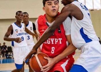 Liberian youth basketball player in white jersey defending an Egyptian opponent during a FIBA-sanctioned game.