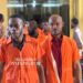 Defendants in orange prison uniforms escorted to court during the Capitol Building arson case in Monrovia