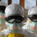 Liberian health workers in full protective gear during Ebola response, as the Health Ministry issues an alert and quarantines contacts after a suspected Ebola death.