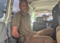 Ecobank robbery suspect Fobay Emery Johnson seated inside a police vehicle in Monrovia, accused of armed robbery and citing mental illness in court.