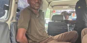 Ecobank robbery suspect Fobay Emery Johnson seated inside a police vehicle in Monrovia, accused of armed robbery and citing mental illness in court.