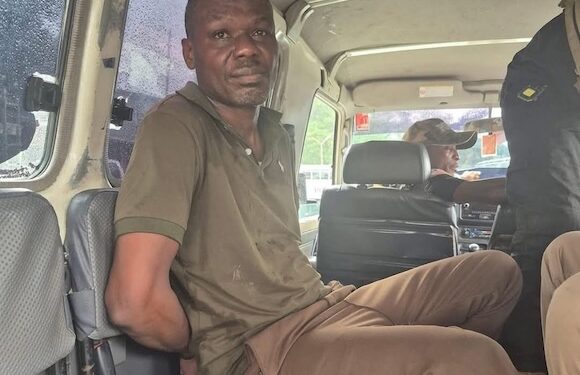 Ecobank robbery suspect Fobay Emery Johnson seated inside a police vehicle in Monrovia, accused of armed robbery and citing mental illness in court.