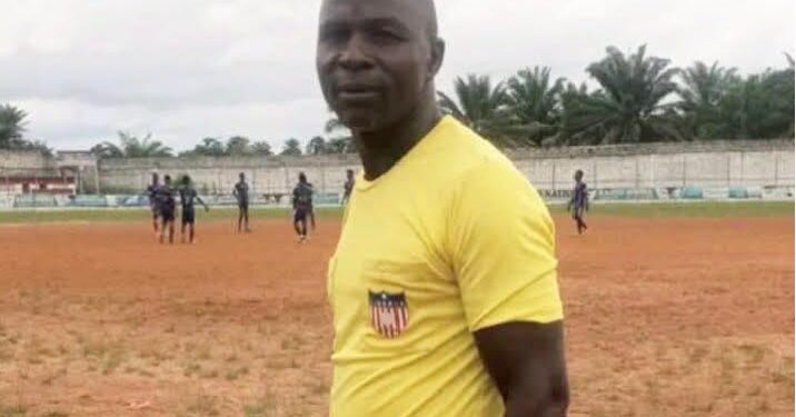 Liberian kickball referee Julius Suah standing on a dirt pitch during a local tournament in Nimba County before his arrest for alleged fuel theft