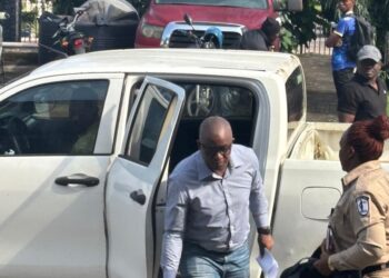 Former LTA chair Abdullai Kamara escorted by officers as he exits a prison transport vehicle after bond approval in Monrovia.